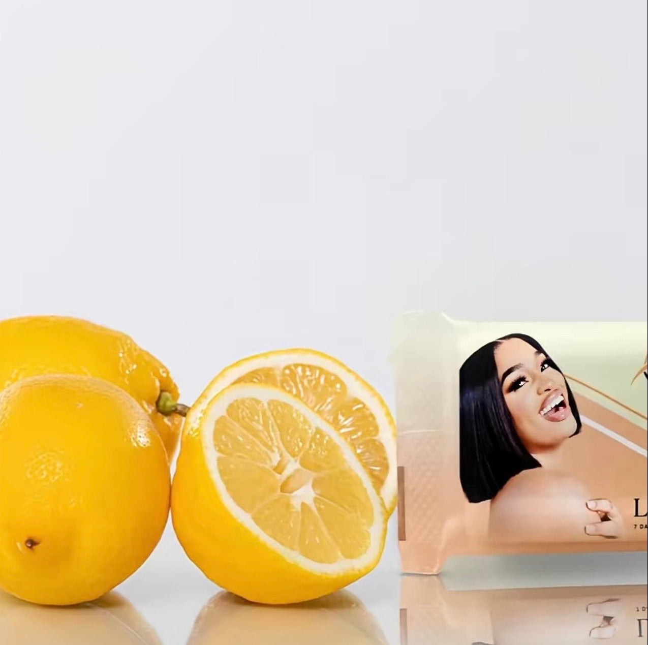Two lemons and a skincare product packaging with a woman's face on a white background